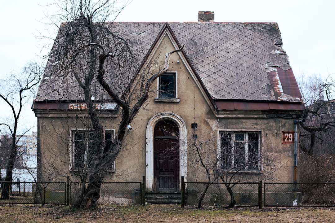 an-old-house-with-a-fence-around-it-f8xvg1a28ie